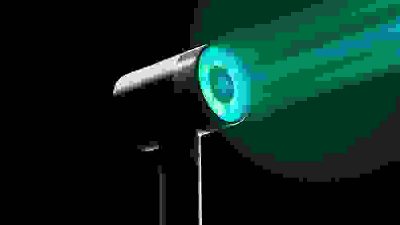 A L’Oreal Airlight Pro shining a teal-colored ray of light in the dark.
