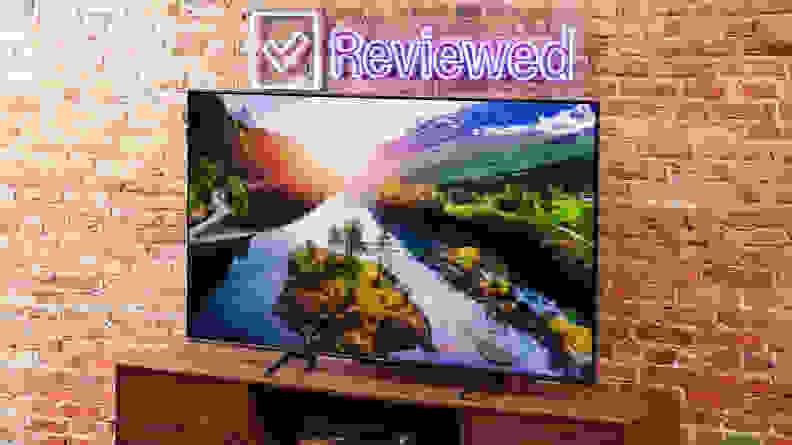 The Hisense U6K Mini-LED TV on a table with a brick background.