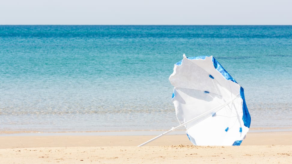 A blue and white umbrella blows in the wind