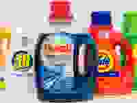 Five bottles of liquid laundry detergent stand in a row