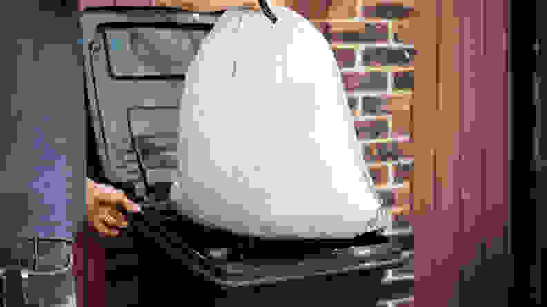 A person throwing a trash bag into a trash bin.