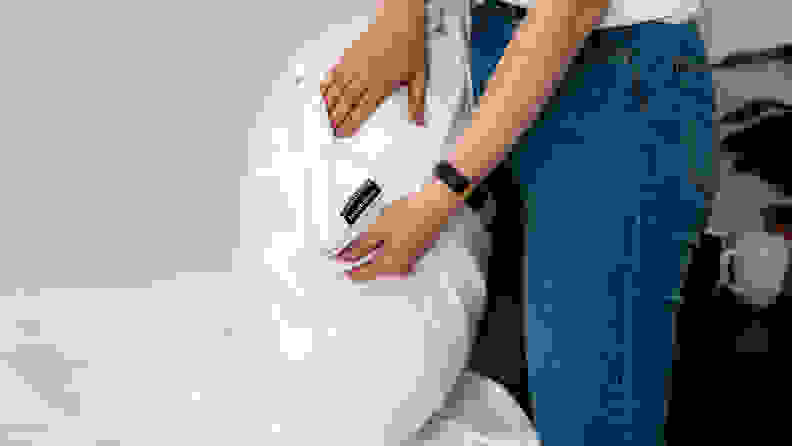 a woman pulls the Brooklinen pillow protector off a pillow