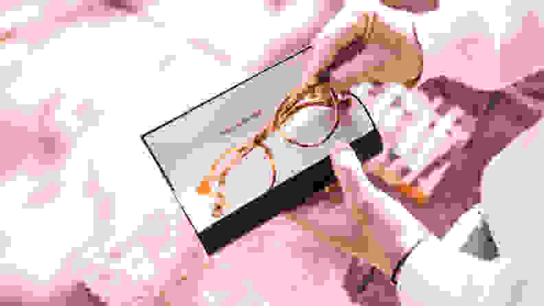 A person pulls out a pair of eyeglasses from inside its case.