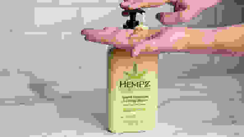 A person's hand pumping a yellow bottle of body lotion.