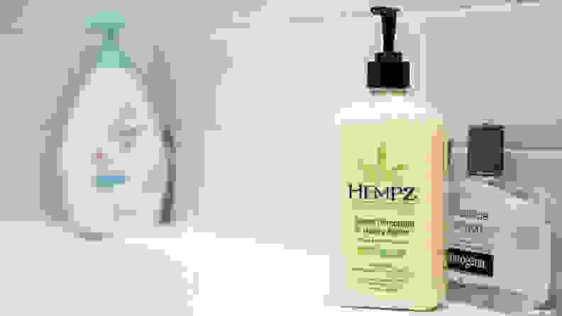 A yellow bottle of Hempz Moisturizing Skin body lotion standing on the side of a tub.