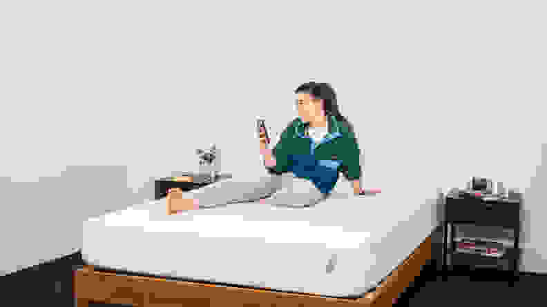 A woman sits on the Tuft & Needle Original mattress