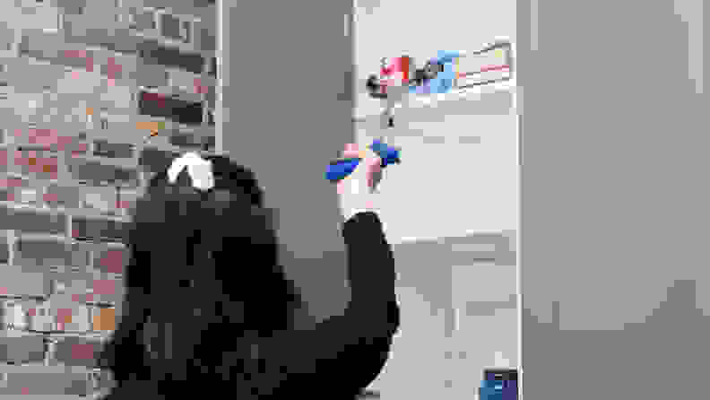 A tester uses a reacher grabber to sbag a can from a high-up shelf