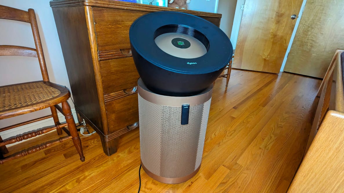 The Dyson Big and Quiet sits in a home next to a wood cabinet and chair.