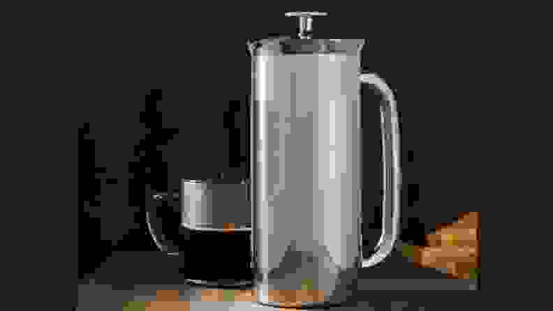 Espro French press besides a cup of coffee on a wooden surface