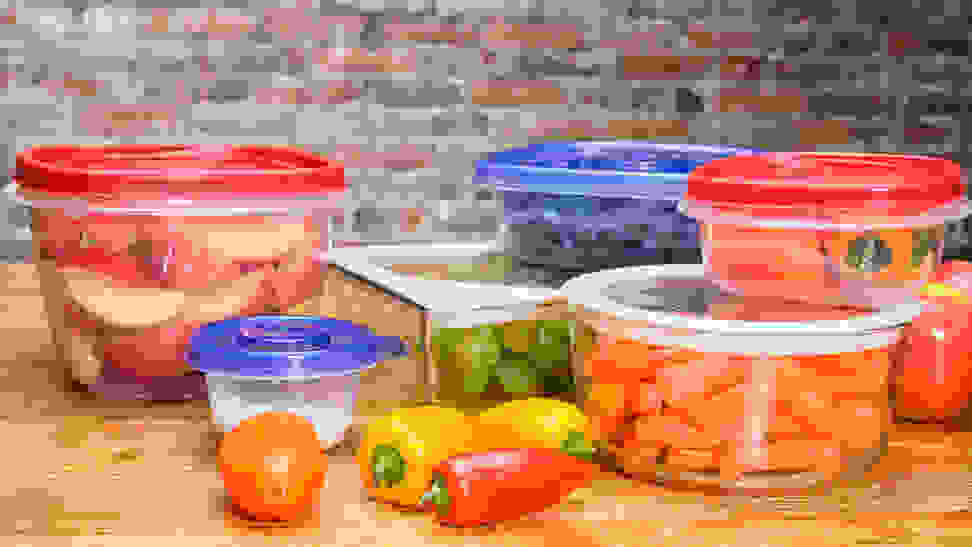 Several food strage containers filled with fresh produce on a wooden surface