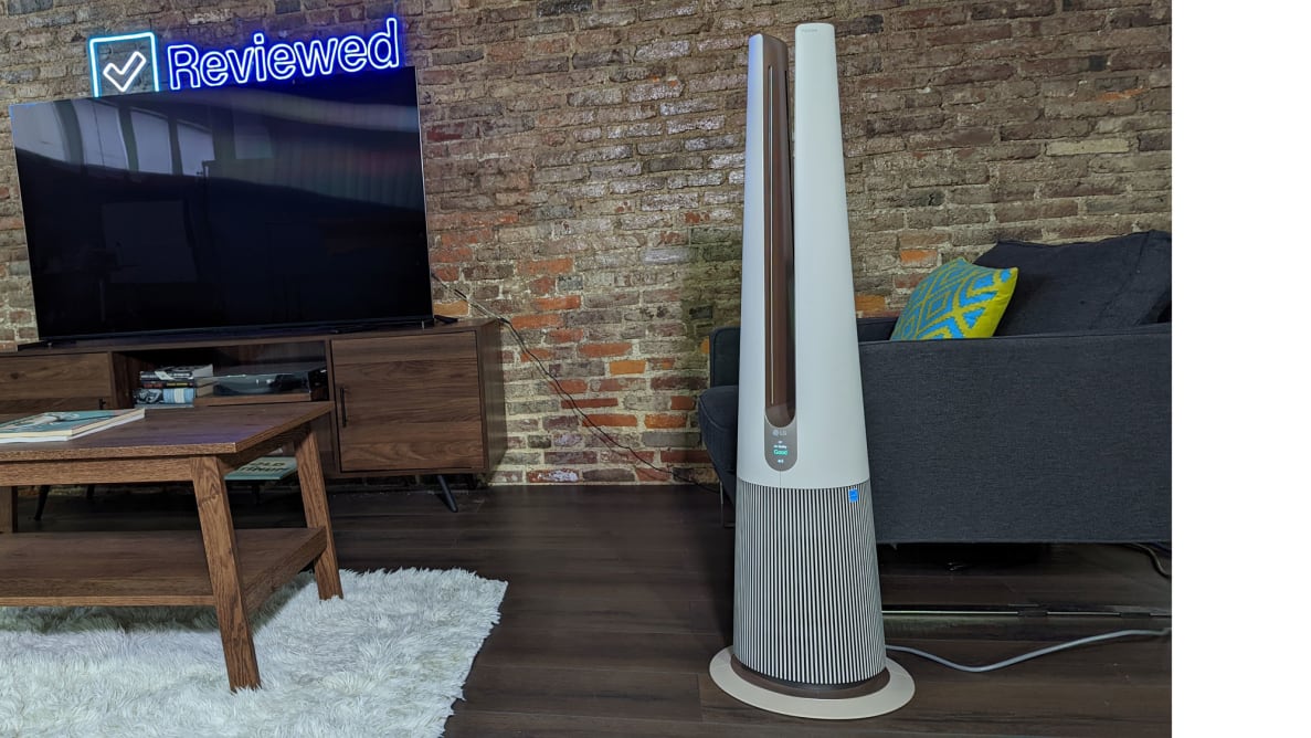 A tall air purifier sits in a living room with a TV and coffee table.
