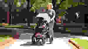 Woman walking in the park with the Bugaboo Fox 5 stroller in the color black.