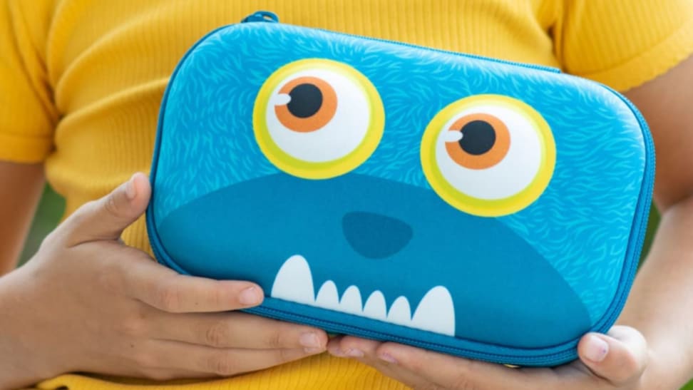 Blue monster pencil case being held by child in a yellow shirt.