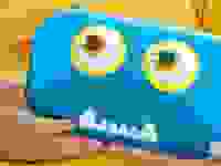 Blue monster pencil case being held by child in a yellow shirt.