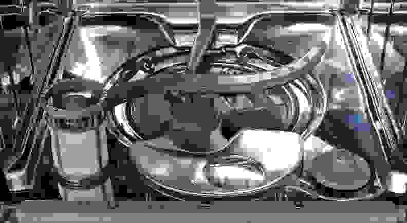 The bottom interior of a dishwasher with the filter removed and sitting next to its opening.