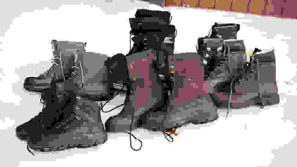 A wide selection of men's winter boots, sitting on a bank of snow.