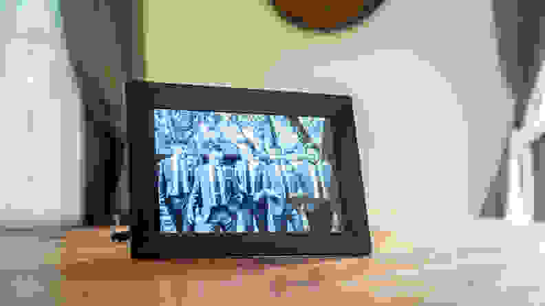 The Nixplay digital picture frame displays a black-and-white image of groomsmen.