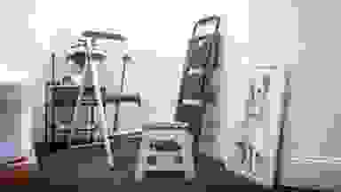 A grouping of three step stools stand in an office next to a portrait of a dog