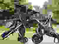 Three different strollers balance on top of each other on the sidewalk.