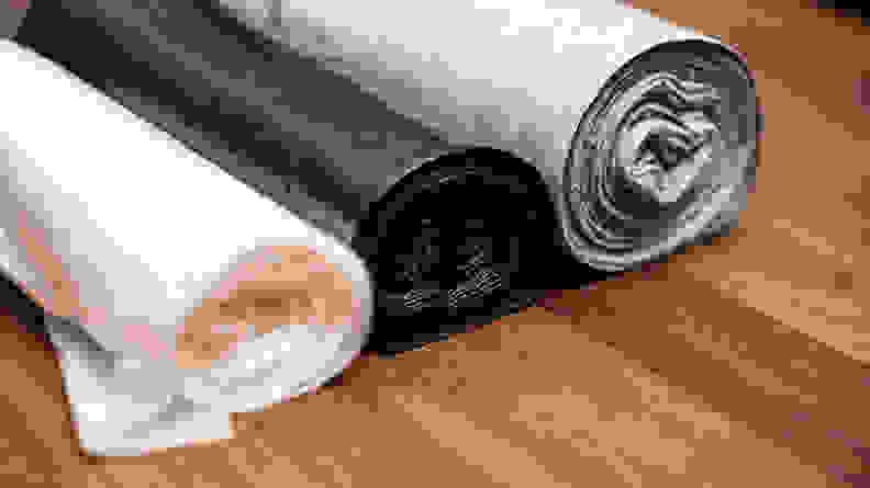 Three rolled up trash bags in a row.