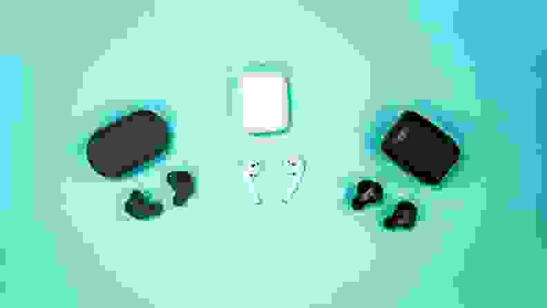 Three sets of true wireless earbuds and their cases on a cyan backdrop