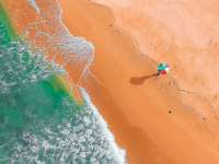 Aerial shot of a lone beach umbrella on a beach