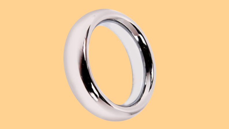 A single stainless steel cock ring from T-Language in front of an orange background.