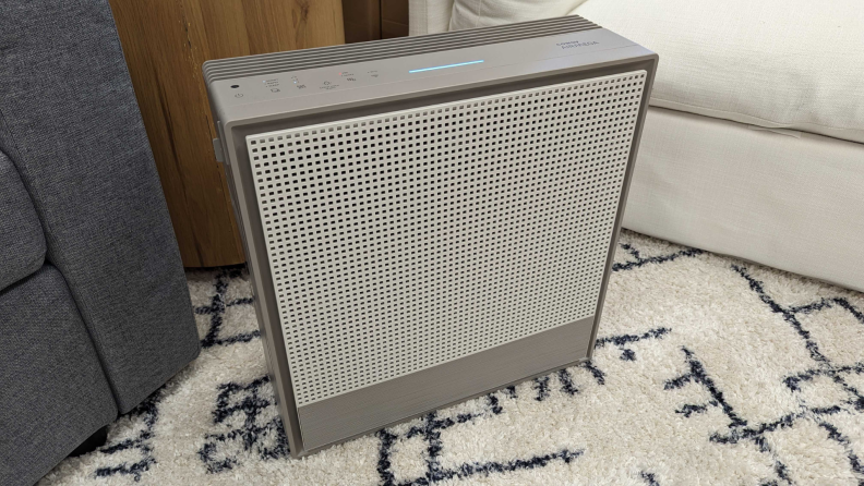 A Coway Airmega 250S sits in a living room next to a couch.