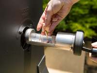Girl putting wood chips into an electric smoker.