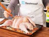 A person brushing a spatchcocked turkey with cooking oil