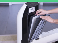 Person using hands to change air filter on small white air purifier.