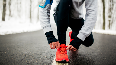 Girl bending down to tie her shoes on a winter run.