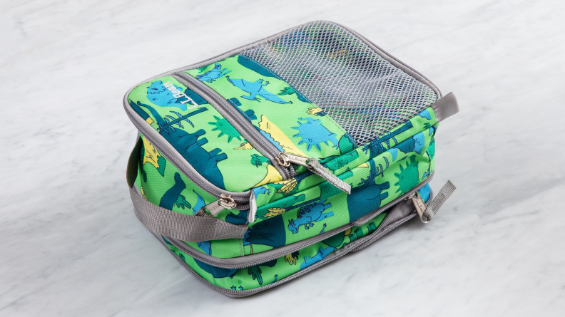 The L.L. Bean Expandable Lunch Box in green dinosaur print on a marble counter.