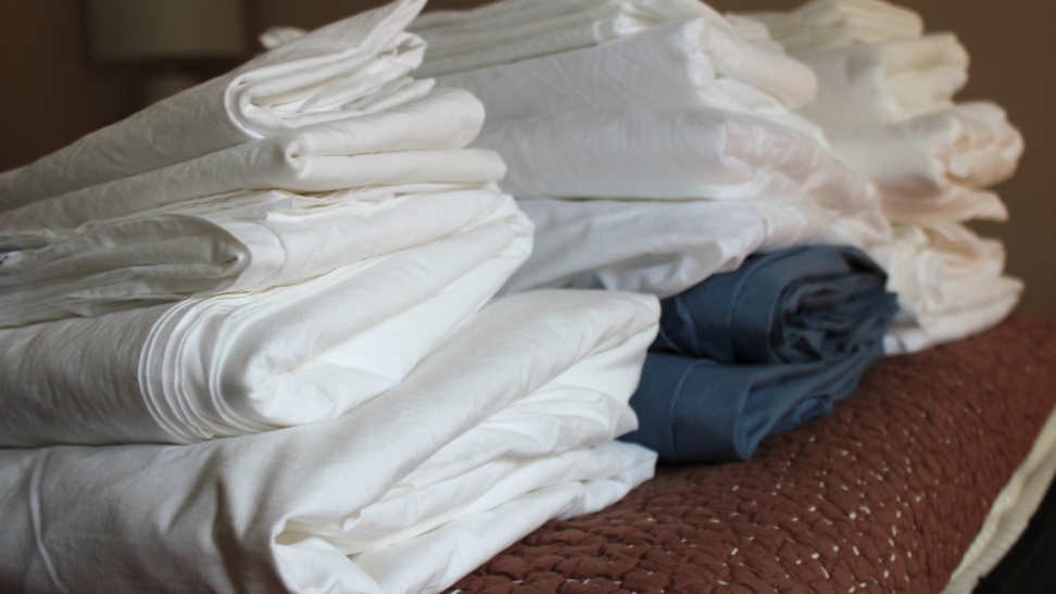 Three stacks of the best percale sheets we tested, folded on a table.