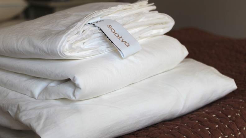 A set of white Saatva sheets folded on a table.