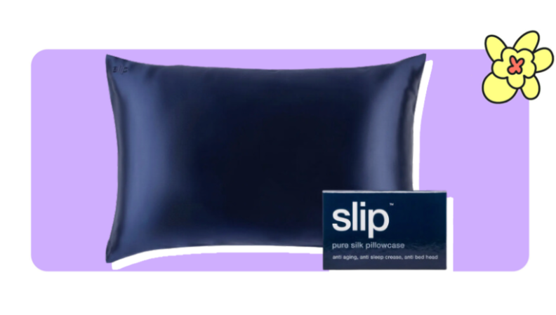 A navy blue Pure Silk Pillowcase from Slip next to a small cardboard box in front of purple background with a yellow cartoon flower in the corner.
