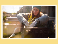 Person smiling while gardening outside in the cold against a yellow background.